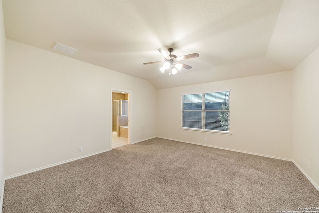 spare room featuring ceiling fan, light carpet, and vaulted ceiling