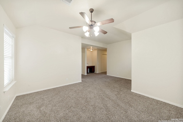 carpeted spare room featuring a wealth of natural light, ceiling fan, and lofted ceiling