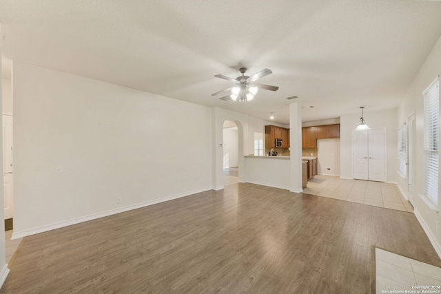 unfurnished living room with ceiling fan and light hardwood / wood-style flooring