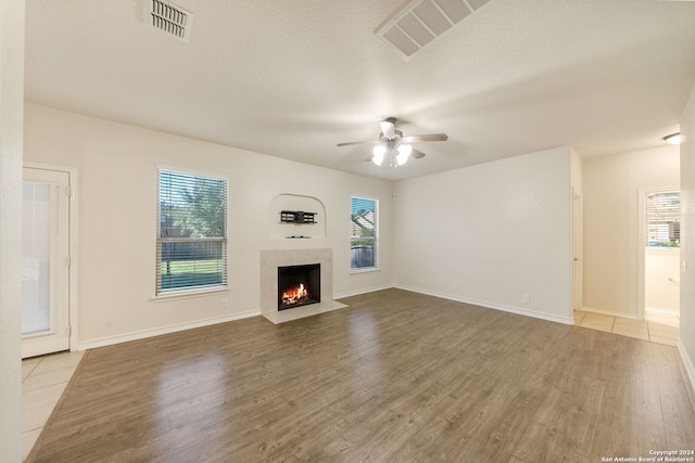 unfurnished living room with hardwood / wood-style flooring, ceiling fan, and a textured ceiling