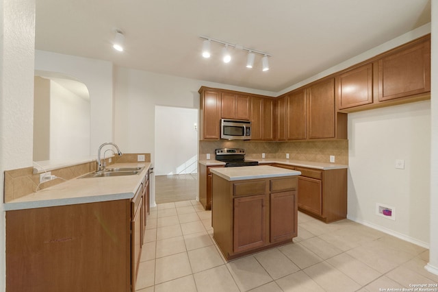 kitchen featuring kitchen peninsula, tasteful backsplash, stainless steel appliances, sink, and light tile patterned floors