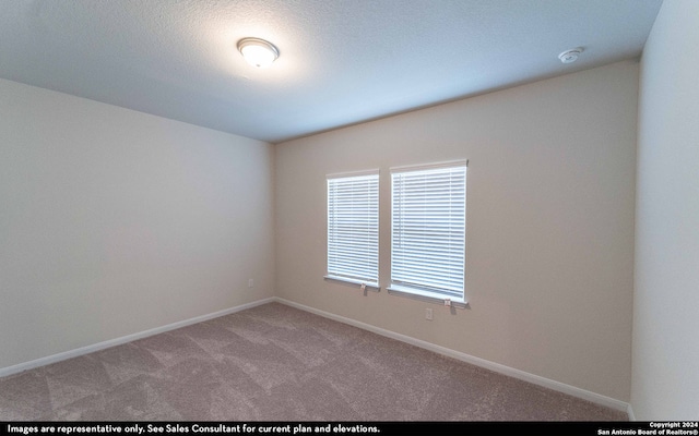 carpeted empty room featuring a textured ceiling