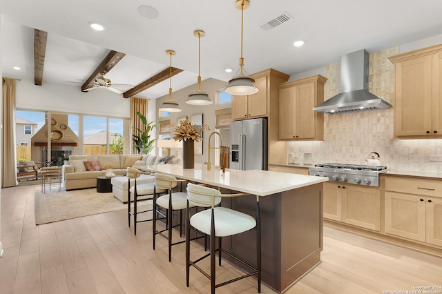 kitchen with light wood-type flooring, stainless steel appliances, ceiling fan, beam ceiling, and wall chimney range hood