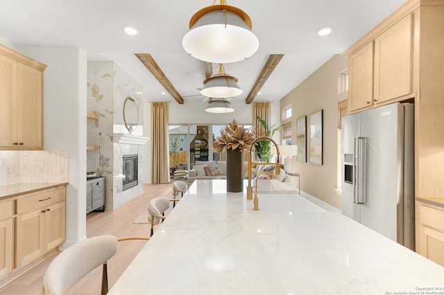 kitchen featuring light wood-type flooring, pendant lighting, high end fridge, a premium fireplace, and beam ceiling