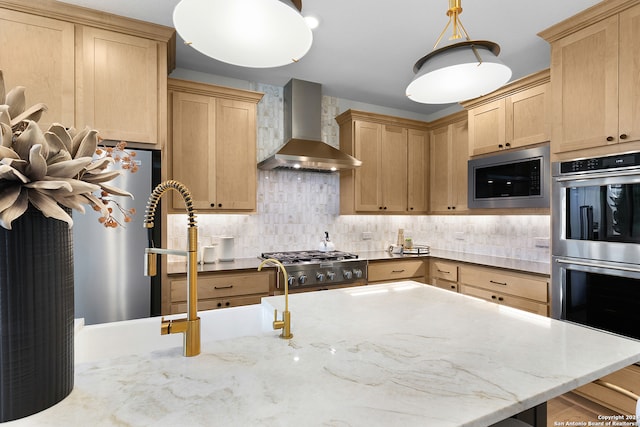 kitchen with wall chimney range hood, hanging light fixtures, stainless steel appliances, and light brown cabinetry