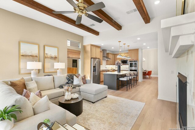 living room with light wood-type flooring, ceiling fan, and beamed ceiling