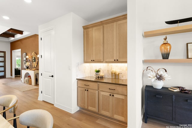 bar featuring light wood-type flooring, light brown cabinetry, backsplash, and beam ceiling