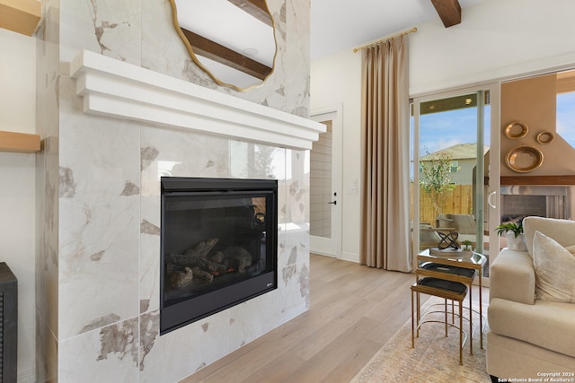 living room featuring light hardwood / wood-style flooring, a high ceiling, a high end fireplace, and beamed ceiling