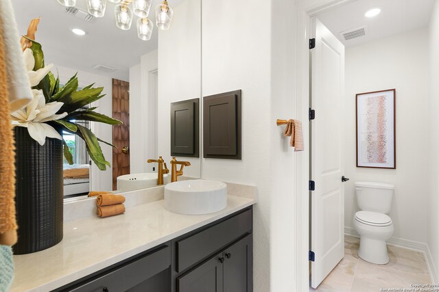 bathroom with vanity, toilet, and an inviting chandelier