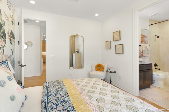 bedroom with ensuite bathroom and light hardwood / wood-style floors