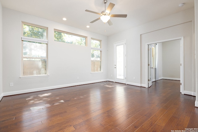 empty room featuring ceiling fan, dark hardwood / wood-style floors, and a healthy amount of sunlight