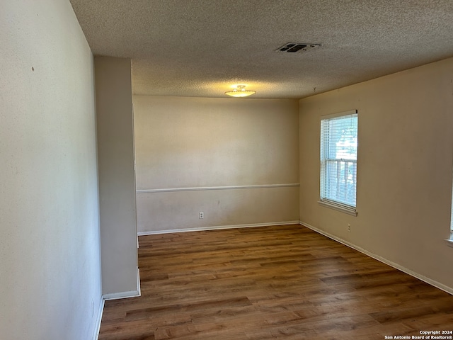 empty room with a textured ceiling and hardwood / wood-style floors