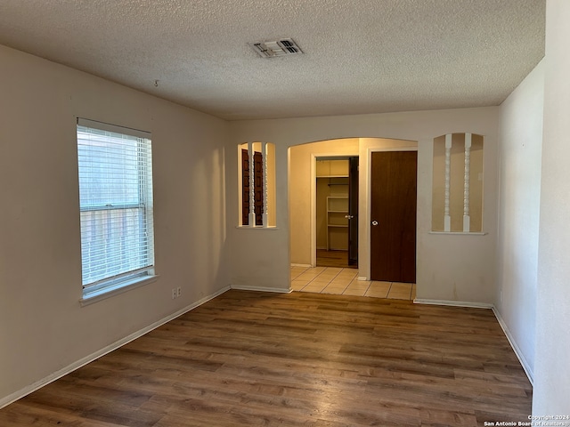 empty room with wood-type flooring and a textured ceiling