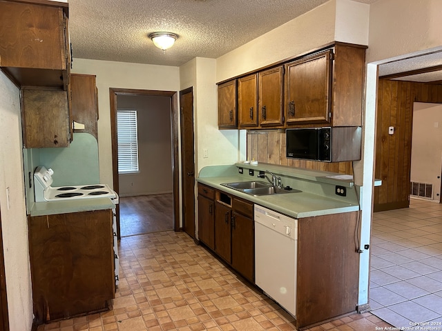 kitchen with a textured ceiling, wood walls, sink, and white appliances