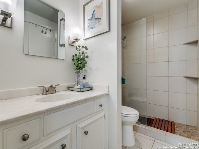 bathroom with vanity, a tile shower, tile walls, toilet, and tile patterned floors