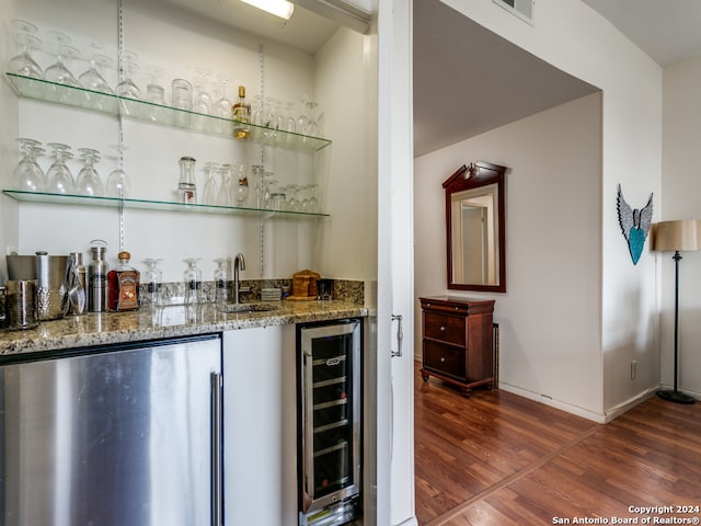 bar with stainless steel fridge, dark hardwood / wood-style flooring, stone countertops, and wine cooler