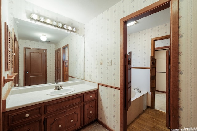 bathroom featuring a bath, hardwood / wood-style floors, and vanity