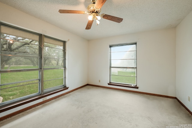 spare room with a textured ceiling, concrete floors, and ceiling fan