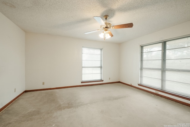 unfurnished room with a textured ceiling, ceiling fan, a wealth of natural light, and concrete floors