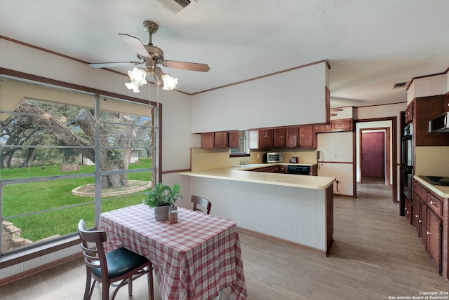 kitchen featuring light wood-type flooring, crown molding, black appliances, kitchen peninsula, and ceiling fan