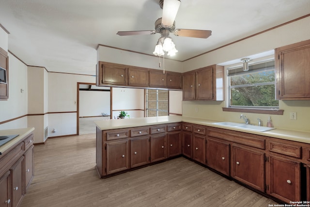 kitchen with kitchen peninsula, sink, ceiling fan, and light hardwood / wood-style floors