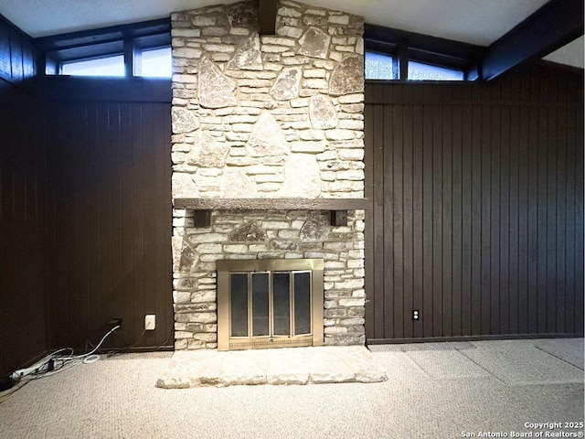 interior space featuring lofted ceiling, wooden walls, carpet flooring, a fireplace, and a healthy amount of sunlight