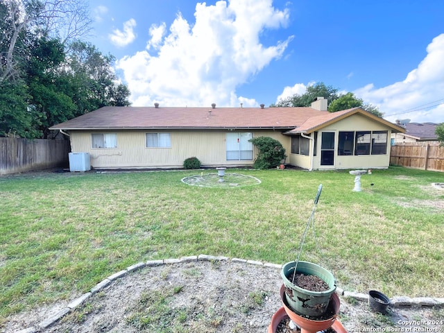 rear view of property featuring a sunroom, central air condition unit, and a lawn