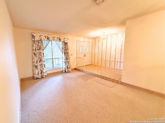 carpeted empty room featuring a notable chandelier and a textured ceiling