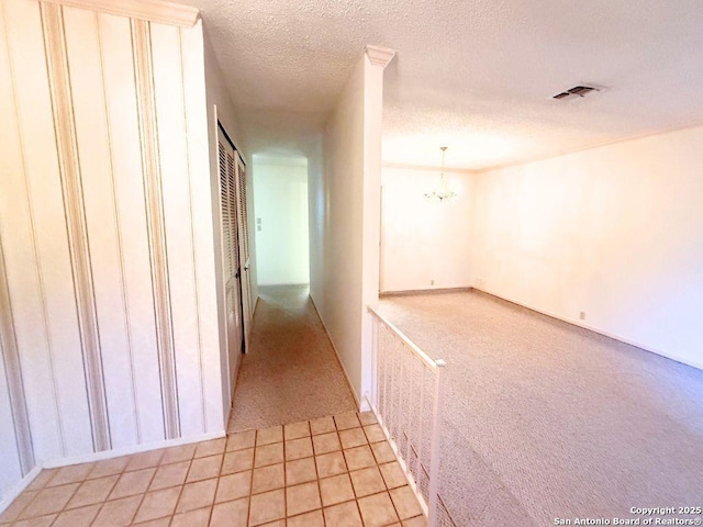 hallway with a notable chandelier and a textured ceiling