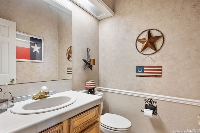 bathroom with vanity, toilet, and backsplash