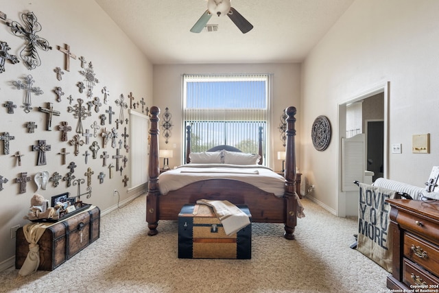 bedroom with ceiling fan, light colored carpet, and a textured ceiling