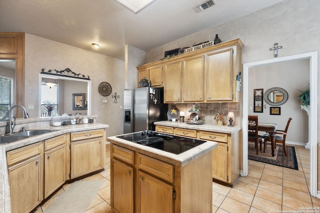 kitchen with stainless steel fridge, backsplash, a center island, sink, and black electric stovetop