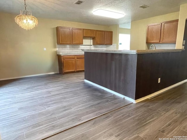 kitchen featuring pendant lighting, a textured ceiling, a notable chandelier, and dark hardwood / wood-style floors