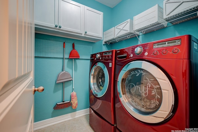 clothes washing area with light tile patterned floors, cabinets, and washing machine and clothes dryer