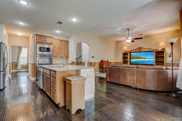 kitchen featuring appliances with stainless steel finishes, ceiling fan, dark wood-type flooring, and a kitchen island with sink