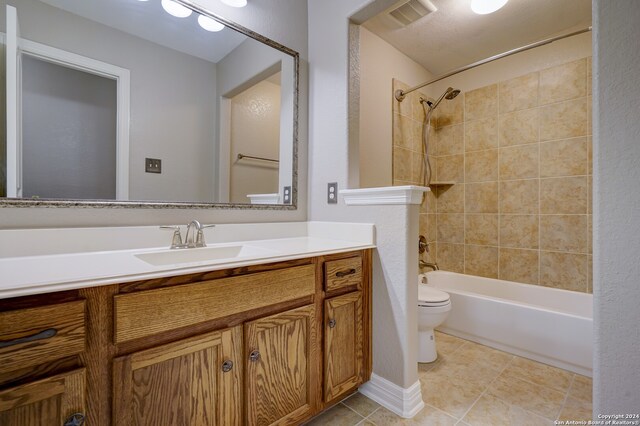 full bathroom with tiled shower / bath, vanity, toilet, and tile patterned floors