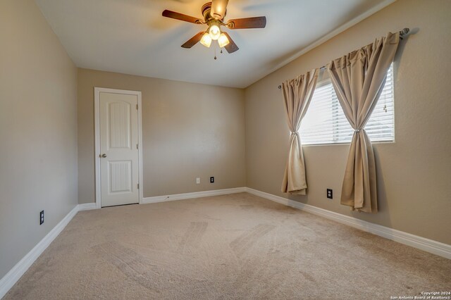 spare room featuring light carpet and ceiling fan