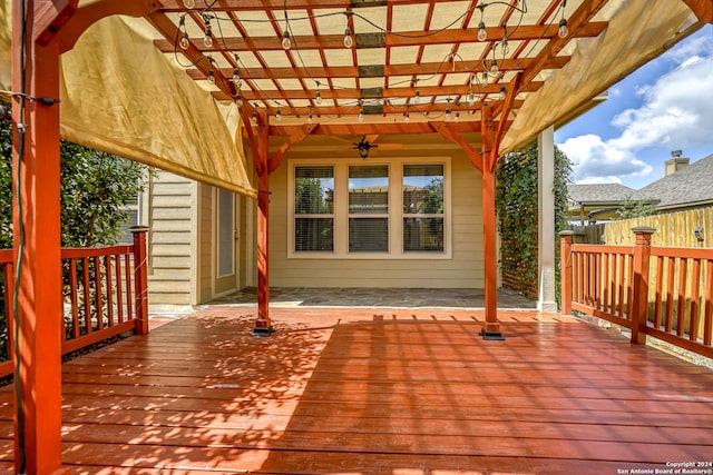 wooden deck featuring ceiling fan and a pergola