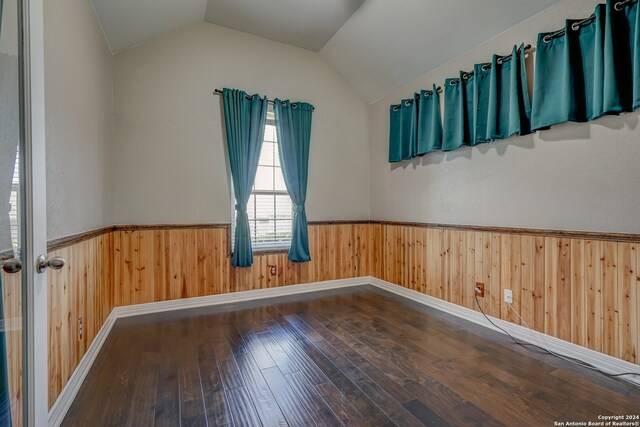 spare room with hardwood / wood-style floors, wood walls, and vaulted ceiling