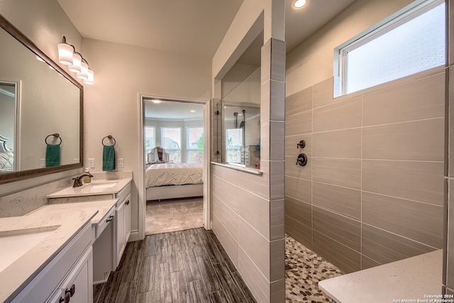 bathroom featuring hardwood / wood-style flooring, a tile shower, and vanity