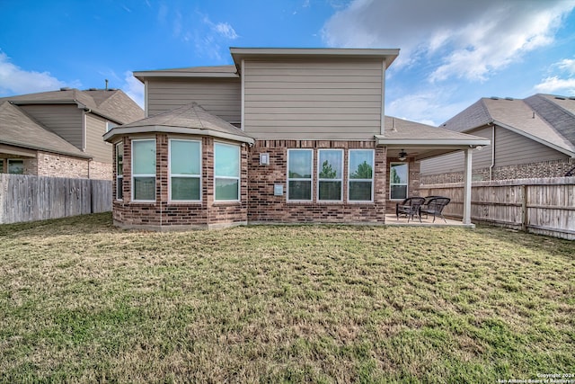 rear view of house featuring ceiling fan, a yard, and a patio area