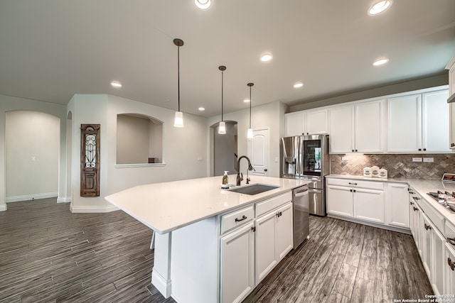 kitchen featuring hanging light fixtures, sink, white cabinets, and a kitchen island with sink