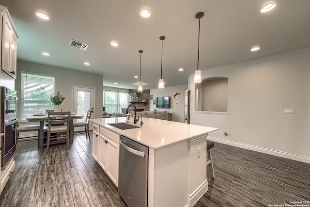 kitchen featuring a kitchen island with sink, white cabinetry, dishwasher, sink, and hanging light fixtures