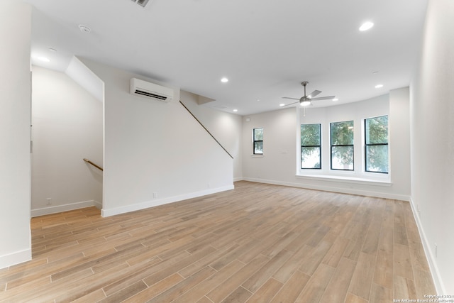 unfurnished living room featuring a wall unit AC, light wood finished floors, recessed lighting, ceiling fan, and baseboards