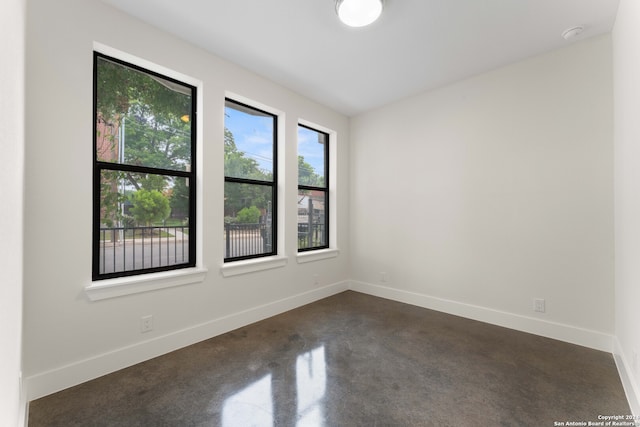 unfurnished room with concrete floors and baseboards