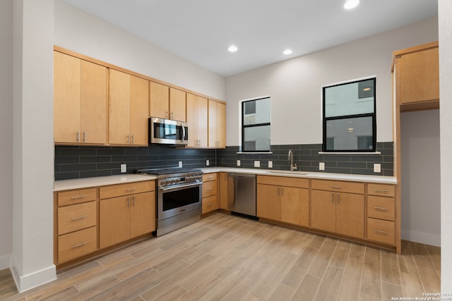 kitchen with appliances with stainless steel finishes, light countertops, a sink, and light brown cabinets