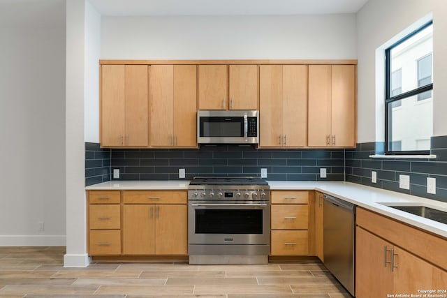 kitchen with decorative backsplash, stainless steel appliances, light countertops, and wood finish floors