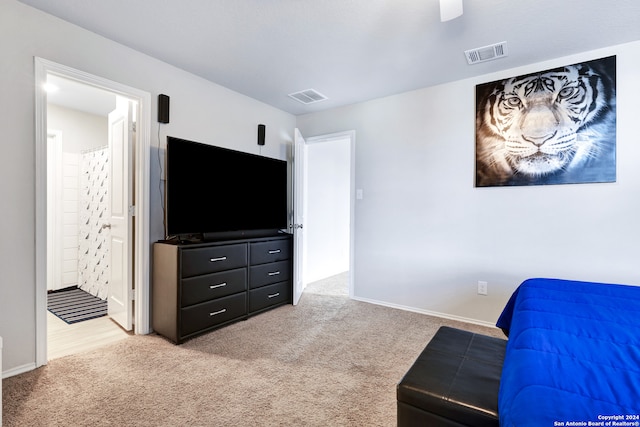 bedroom with light carpet, ensuite bathroom, and ceiling fan