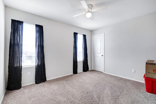 carpeted spare room featuring ceiling fan