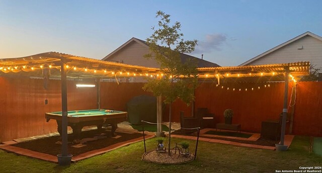 back house at dusk with a yard, a pergola, and a patio area